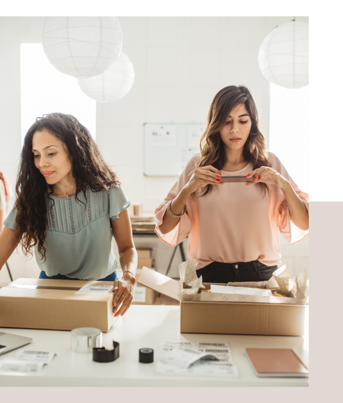 Two women collaborating on a laptop in a modern office setting, focused on their work.