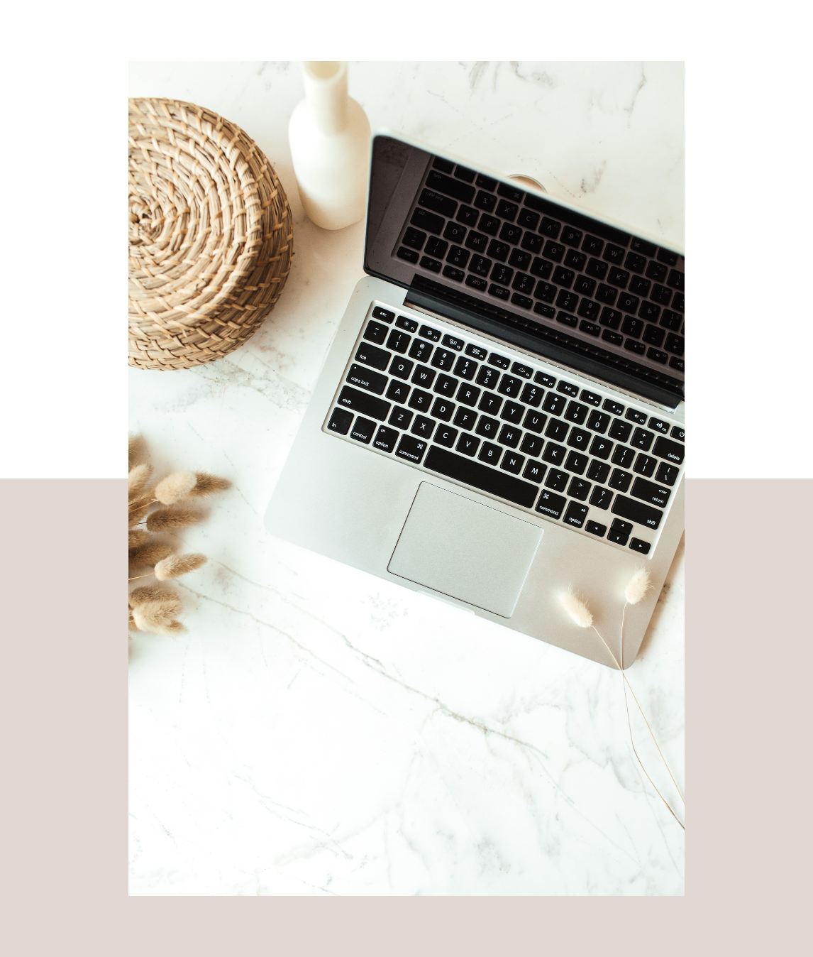 On a marble table, a laptop is accompanied by a wicker basket and a straw hat, evoking a casual, inviting atmosphere.